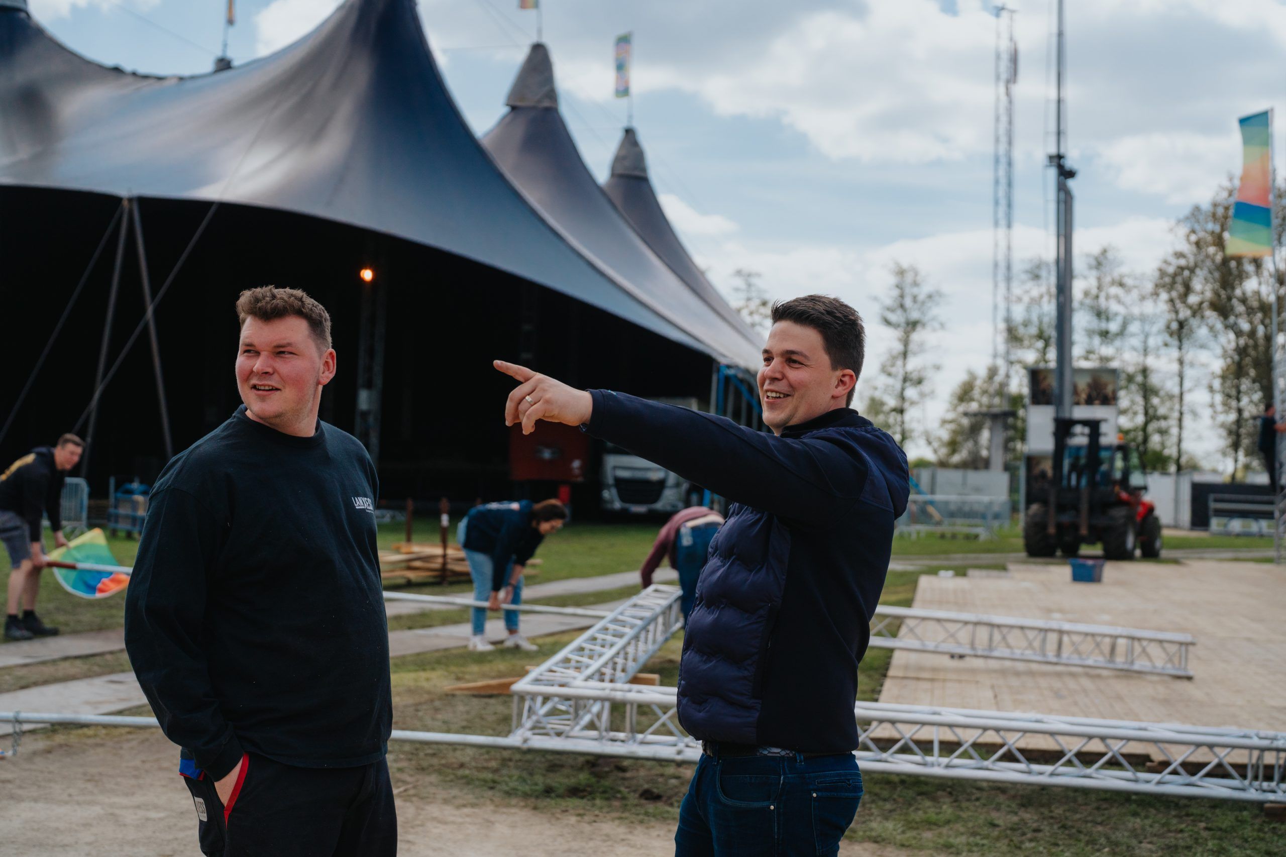 Medewerker wijst richting festivalterrein tijdens de opbouw.