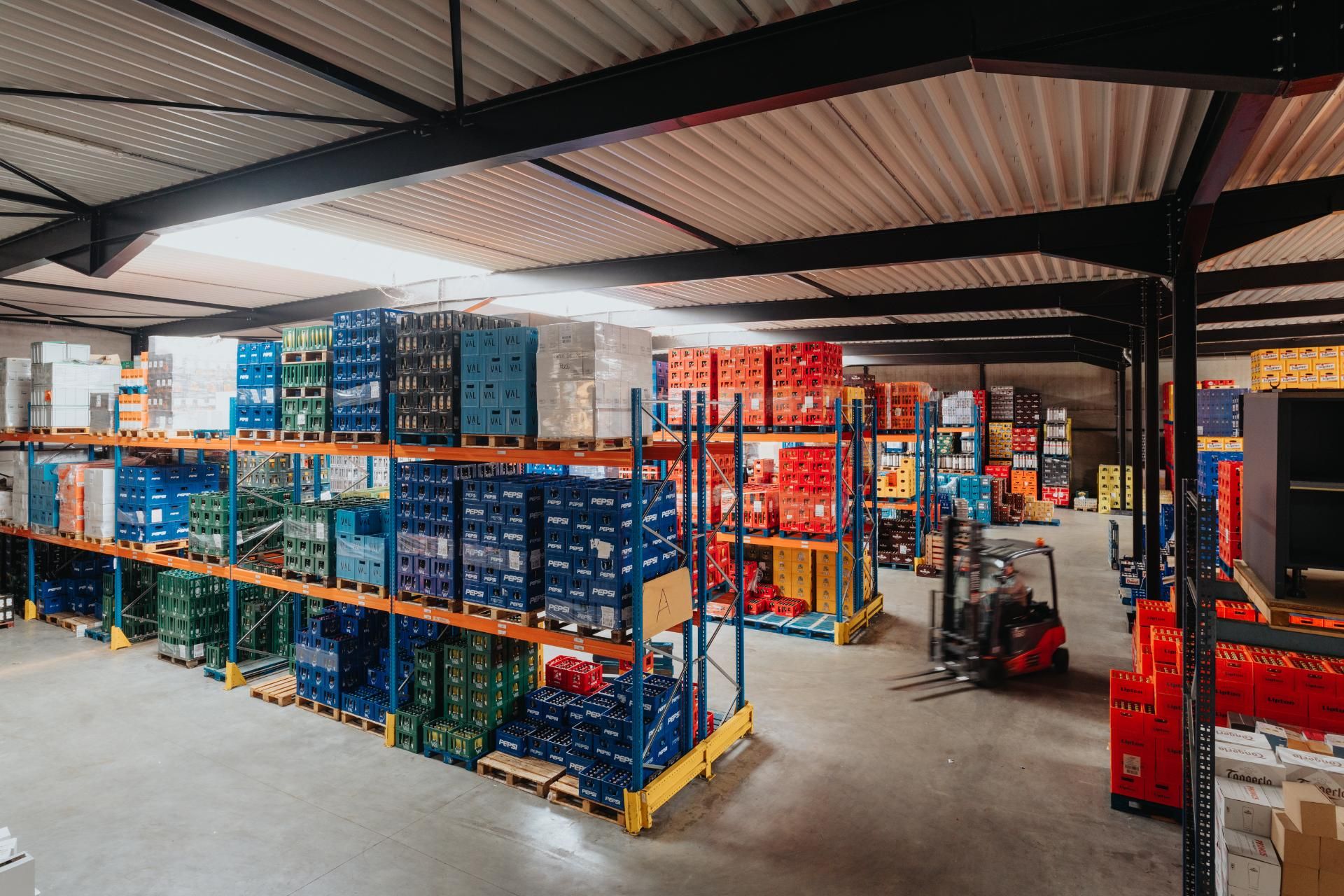 Vorkheftruck rijdt door het drankmagazijn tussen volle rekken.