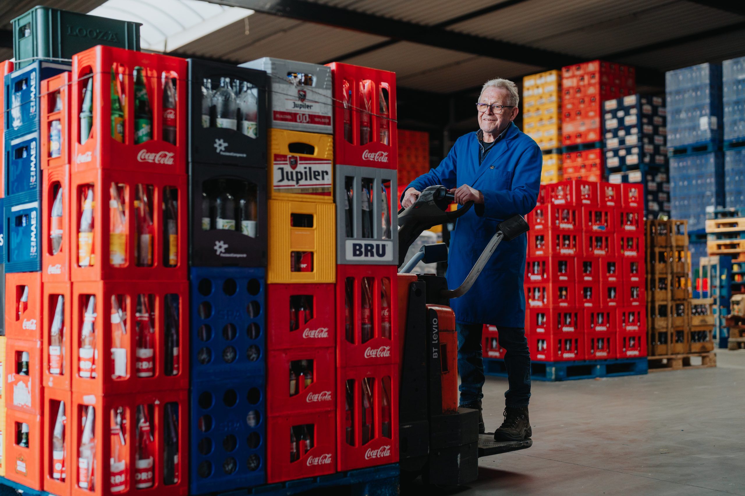 Medewerker verplaatst stapel drankkratten met een elektrische transpallet.